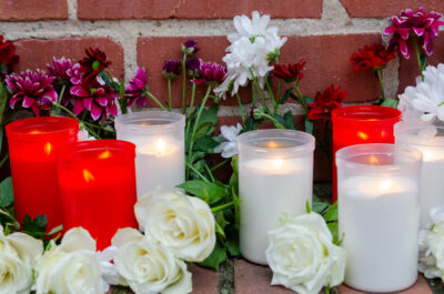 Kerze und Blumen an Mauer